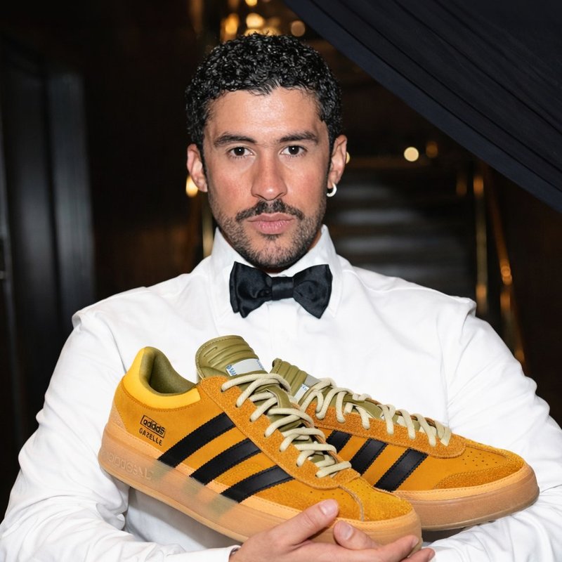 Close-up of a golden canvas sneaker upper with black overlay and snap-on double tongue, showing the Solar Gold Gazelle Indoor design details